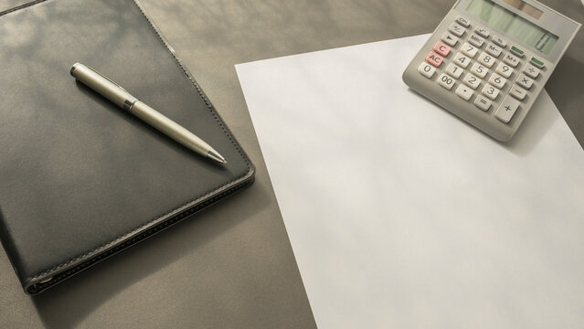 background image . Folder, pen, calculator and white sheet of paper on the table.