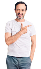 Middle age handsome man wearing casual t-shirt cheerful with a smile on face pointing with hand and...