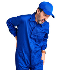Middle age handsome man wearing mechanic uniform suffering of backache, touching back with hand, muscular pain