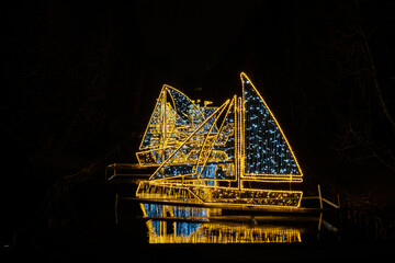 Small ships and Boats Holiday illuminated decorations in Oliva Park Gdansk Poland. Beautiful Christmas fair at night. Advent winter time in Europe background. Christmas Markets in December