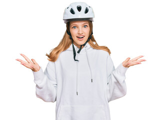 Beautiful young caucasian girl wearing bike helmet celebrating victory with happy smile and winner expression with raised hands
