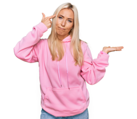 Young blonde woman wearing casual sweatshirt confused and annoyed with open palm showing copy space and pointing finger to forehead. think about it.
