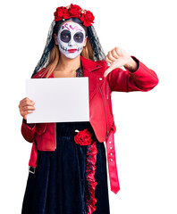 Woman wearing day of the dead costume holding blank empty banner with angry face, negative sign showing dislike with thumbs down, rejection concept