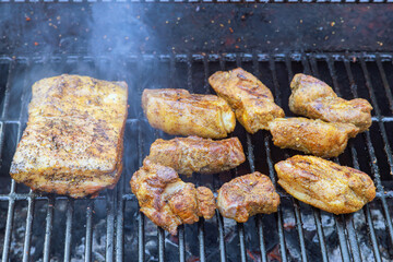 Several large pieces of bacon are grilled smoked on BBQ