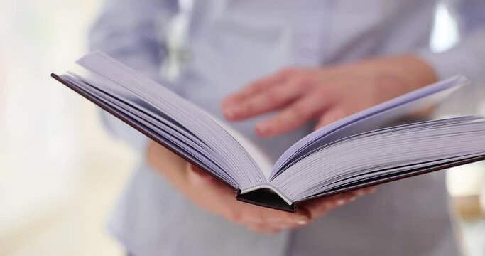 Woman flips through paper book reading useful information