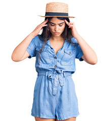Fototapeta premium Brunette teenager girl wearing summer hat with hand on head for pain in head because stress. suffering migraine.