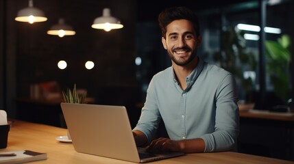 Young Professional Man Smiling and Looking at the Camera while Working with Laptop in the Office
