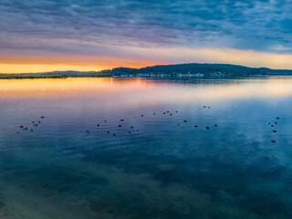 Heavy cloud covered sunrise over the bay with lots of ducks