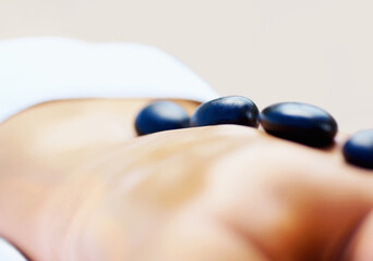 Back, stone massage and person at spa for wellness, holistic therapy or relax in studio on brown...