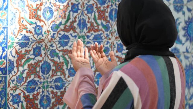 Muslim young woman in hijab is praying in mosque.