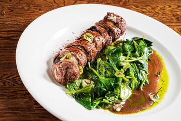 beef with roasted spinach on the wooden background