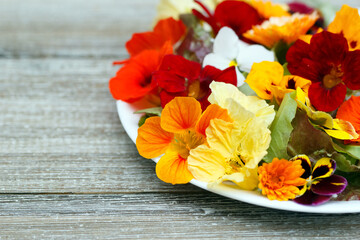 Low calories salad of lettuce and flowers on the wooden table.