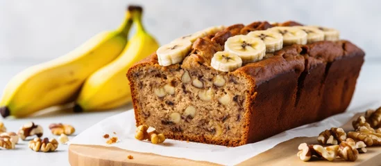 Tuinposter Closeup view of gluten-free banana bread with walnuts and honey sliced on a white marble table. © AkuAku
