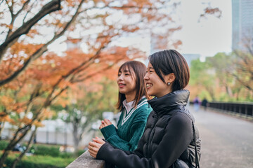 Fototapeta premium 紅葉した木を見ながら話をする女性二人