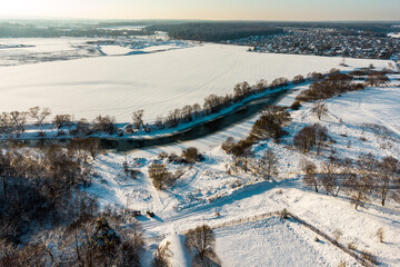 View from above of a river freezing in winter among snowy terrain