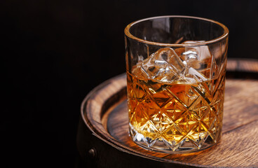 Whiskey glass with ice on a rustic barrel, a classic sip