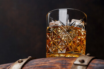 Whiskey glass with ice on a rustic barrel, a classic sip