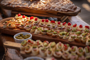 Small sandwiches, canape, served at an event on a wooden board. Different types visible, vegetarian and meat options available.