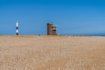The beach with the Old Lifeguard Station and the New Lighthouse in Dungeness, Kent, England, UK
