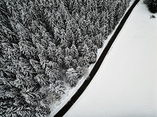 Empty winter road in snow covered forest, top down aerial drone photo, Black Forest, Baiersbronn,...