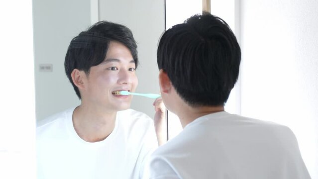 洗面所で歯磨きをする男性