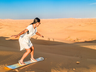 Young women sand surfing at the sand dunes of Dubai United Arab Emirates