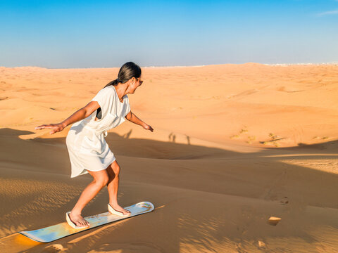 Young women sand surfing at the sand dunes of Dubai United Arab Emirates