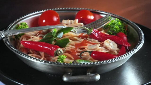 Pasta with vegetables and spices, on the table, in a plate against an old background. Ready food.