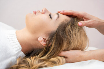 Healer performing set of 32 points of access bars on young woman head, stimulating positive change...