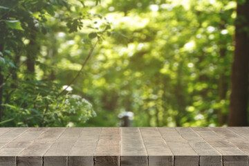 Blank or empty rustic wooden platform with forest or greenery background for product display.