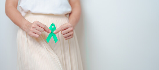 Woman holding Teal Ribbon on abdomen for January Cervical Cancer Awareness month. Uterus and Ovaries, Cervix, Endometriosis, Hysterectomy, Uterine fibroids, Reproductive and World cancer day concept