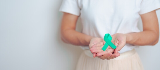 woman holding Teal Ribbon for January Cervical Cancer Awareness month. Uterus and Ovaries, Cervix, Endometriosis, Hysterectomy, Uterine fibroids, Reproductive, Healthcare and World cancer day - obrazy, fototapety, plakaty