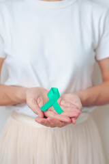 woman holding Teal Ribbon for January Cervical Cancer Awareness month. Uterus and Ovaries, Cervix, Endometriosis, Hysterectomy, Uterine fibroids, Reproductive, Healthcare and World cancer day