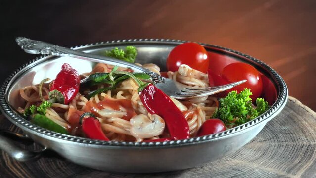 Pasta with vegetables and spices on a table in a plate against an old background. Close-up.