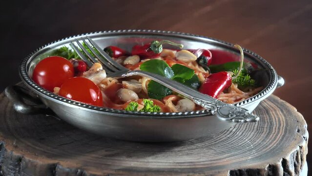 Pasta with vegetables and spices, on the table, in a plate against an old background. Ready food.