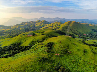 Obraz premium aerial view on the peak in sunset the village far from civilization Traveling on a difficult road. Beautiful sunset view on the hilltop complex. The sun shone through mountain peak after mountain.