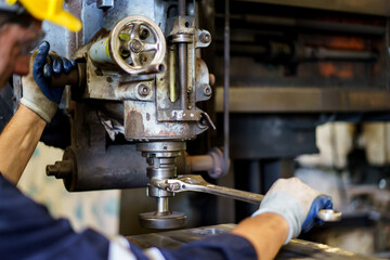 Professional caucasian white ethnicity male technician operating the heavy duty machine in the lathing factory. Technician in safety and helmet suit controlling a machine in factory.