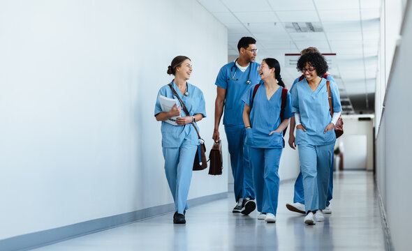 Group of medical interns walking in a hospital corridor, dressed in scrubs
