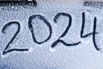 2024 New Year holiday text drawing on snow. Handwriting inscription 2024 date on white surface of...