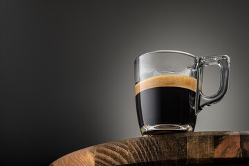 Espresso coffee cup on brown wood table with copy space. Transparent glass mug.