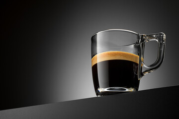 Espresso coffee cup on black table with copy space. Transparent glass mug.