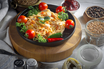 Pasta, spaghetti in a plate with seasonings and vegetables. Hot, natural and tasty dish.