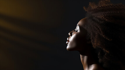 African American woman with curly hair in dark room, side view - obrazy, fototapety, plakaty