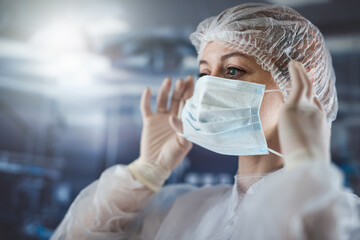  woman doctor in protective suit gloves putting surgical mask at clinic surgery