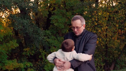 Son runs to meet father in warm embrace in brightly lit autumn park at sunset