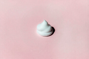 White cosmetic beauty cream swatch swirl isolated on a pink background. Concept of cosmetology and...