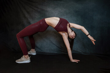 Attractive caucasian slim woman in sport cloth doing yoga stretching at studio black background