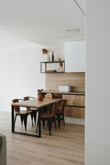 Modern bright kitchen interior with white furniture and wooden dining table