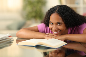 Happy black woman with a book looks at you