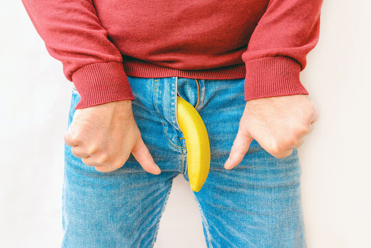 Potency problem concept.Mens denim pants with banana imitating male genitals.Hand shows thumbs down.Health and male sexuality concept.Closeup.